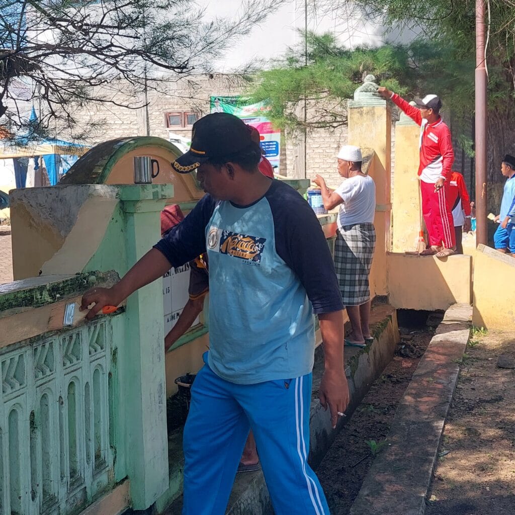 Kepala Desa Galis melakukan pengecatan pagar kantor desa dalam kegiatan gotong royong untuk menciptakan lingkungan kerja yang bersih dan rapi