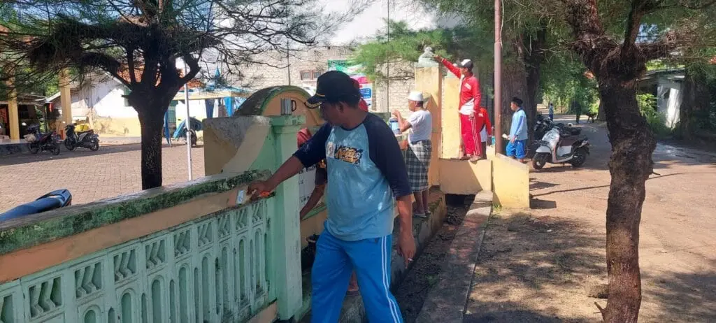 Kepala Desa Galis melakukan pengecatan pagar kantor desa dalam kegiatan gotong royong untuk menciptakan lingkungan kerja yang bersih dan rapi