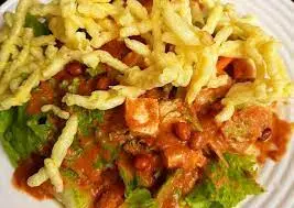 Asinan sayur Betawi segar disajikan dengan bumbu kacang yang lezat, lengkap dengan taburan kacang goreng, kerupuk mie kuning, dan kerupuk merah, siap untuk dinikmati