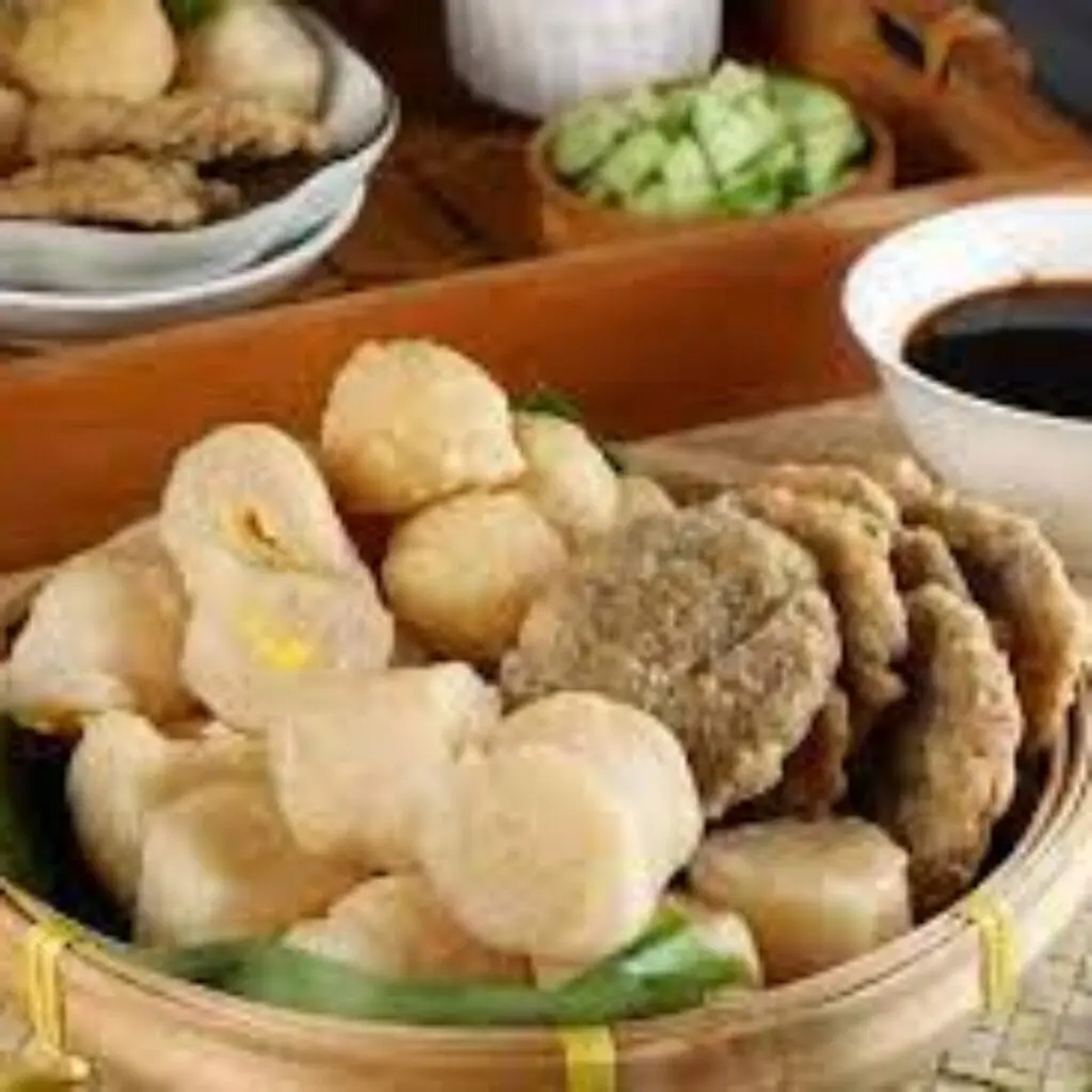 Pempek Sutra Udang dengan Cuko Pedas: Pempek sutra bertekstur lembut, terbuat dari udang segar dan tepung tapioka, disajikan dengan kuah cuko pedas yang khas. Cuko ini dibuat dari gula merah, cabe rawit, dan bumbu rempah lainnya yang membuat rasanya semakin sedap