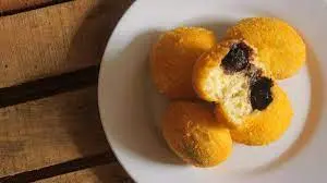 Bola-bola tape singkong goreng, atau peuyeum ball, disajikan dengan taburan keju parut di atasnya, siap menjadi cemilan lezat yang empuk di dalam dan renyah di luar