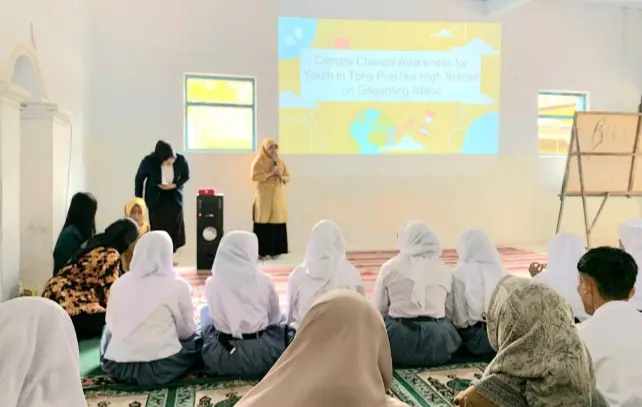 Ketua Tim Pengabdian Kepada Masyarakat Restu Karlina Rahayu, S.IP.,M.Si.,PhD (berdiri berbaju kuning) saat memberikan pengarahan kepada para siswa dan guru SMA Toha Praktika Giligenting Sumenep terkait climate change, Senin (21/8/2023)
