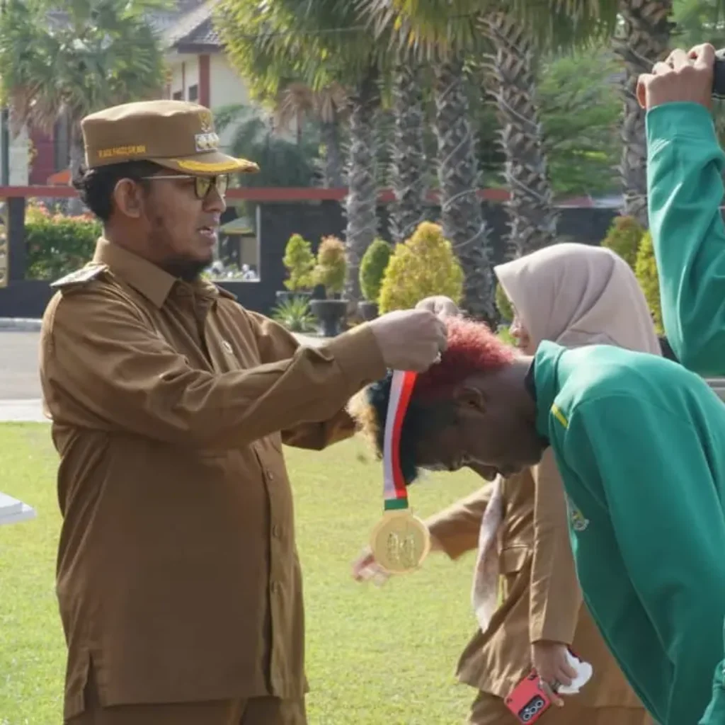 Bupati Sumenep Achmad Fauzi Wongsojudo menyerahkan penghargaan kepada atlet peraih medali PON XXI Aceh-Sumut dan kafilah MTQ Nasional XXX di halaman Kantor Bupati Sumenep
