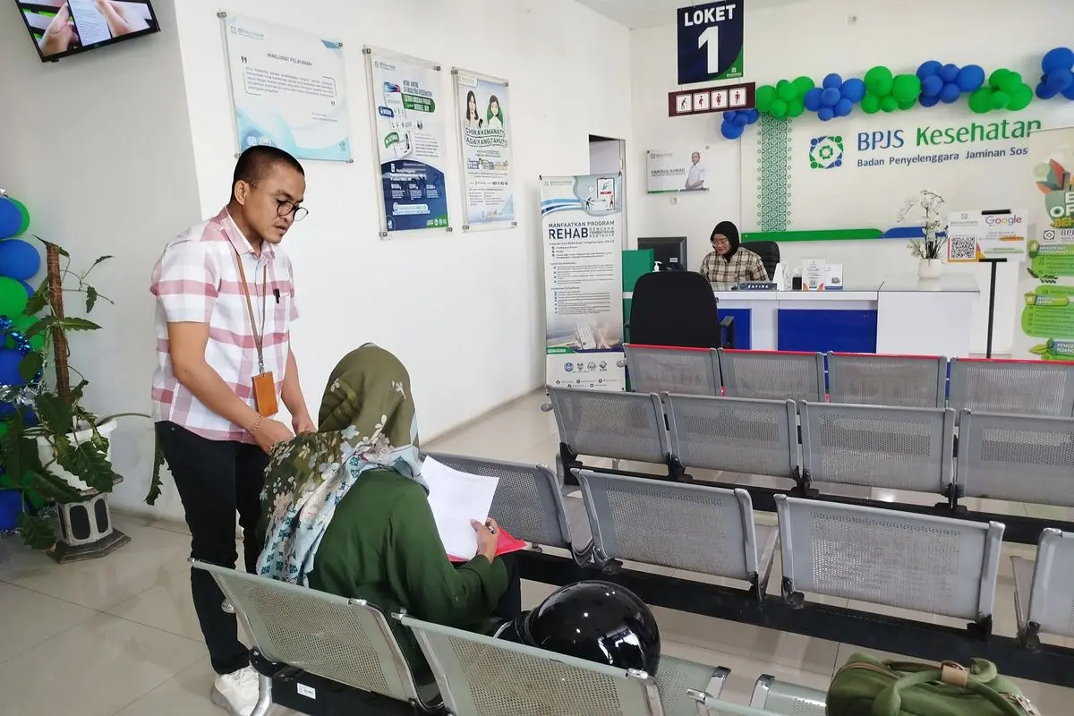 Kepala Bagian Sumber Daya Manusia, Umum, dan Komunikasi BPJS Kesehatan Wilayah Madura, Ary Udiyanto saat membantu salah satu peserta BPJS Kesehatan di kantor BPJS Kesehatan Bangkalan
