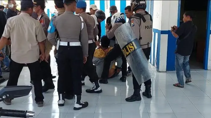 Sejumlah anggota polisi saat memisahkan atau mengamankan salah satu pendomo (kaos kuning) ke Pos Lantas saat aksi mahasiswa memblokade jalan raya jalur nasional di Jalan Jaksa Agung Suprapto, Kecamatan/Kabupaten Sampang, Madura, Minggu (31/8/2025)