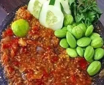 Sambal terasi pedas dengan petai, mentimun, kemangi, dan jeruk limau di cobek batu