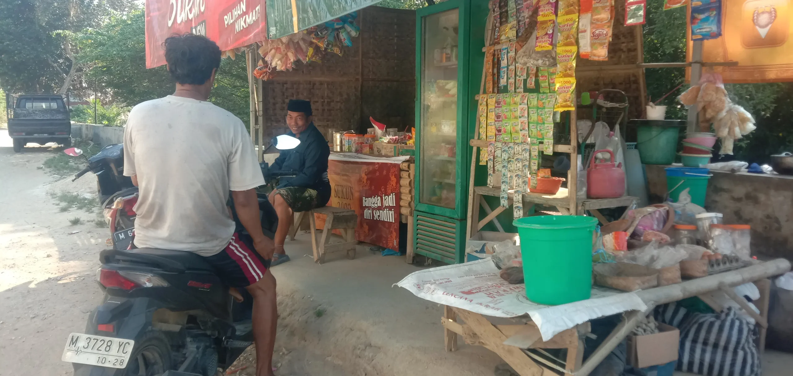 Bapak Ahmad melayani pelanggan di toko kelontong yang buka hingga malam di Sumenep