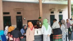 Babinsa Koramil Gapura mengawal pembagian bantuan beras dan minyak goreng kepada warga Desa Gapura Sumenep