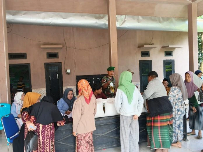Babinsa Koramil Gapura mengawal pembagian bantuan beras dan minyak goreng kepada warga Desa Gapura Sumenep