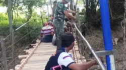 Warga Desa Nyormanis dan Babinsa Koramil Blega memperbaiki jembatan rusak akibat banjir di Kecamatan Blega, Bangkalan.