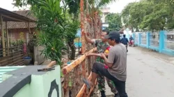 Babinsa Koramil Sapeken membantu warga membangun pagar rumah di Desa Pagerungan Kecil Kabupaten Sumenep
