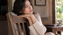 Reni duduk di kursi kayu tua sambil mengenang kakeknya dalam cerpen Kenangan di Kursi Tua